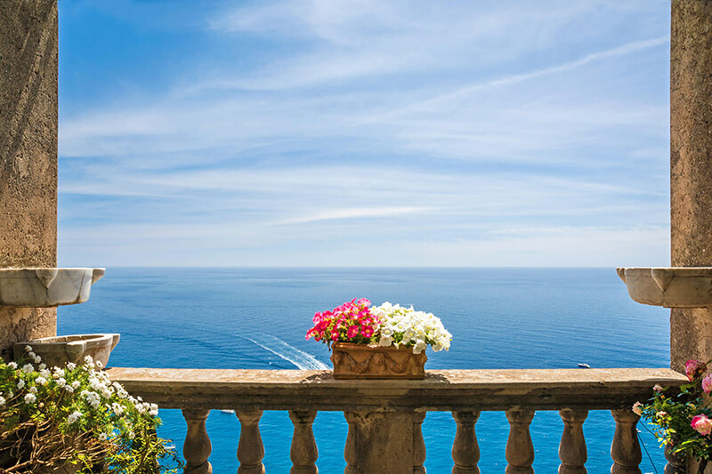 Aerial view of a restaurant overlooking a long coastline with a yacht sailing in the sea